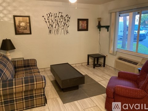 A beige sofa sits in a living room with a lamp and decorations on the wall.