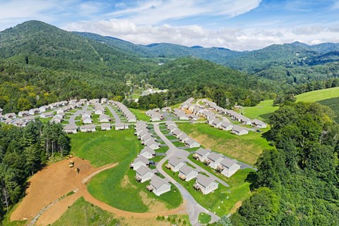 A bird's eye view of a residential area surrounded by green hills.