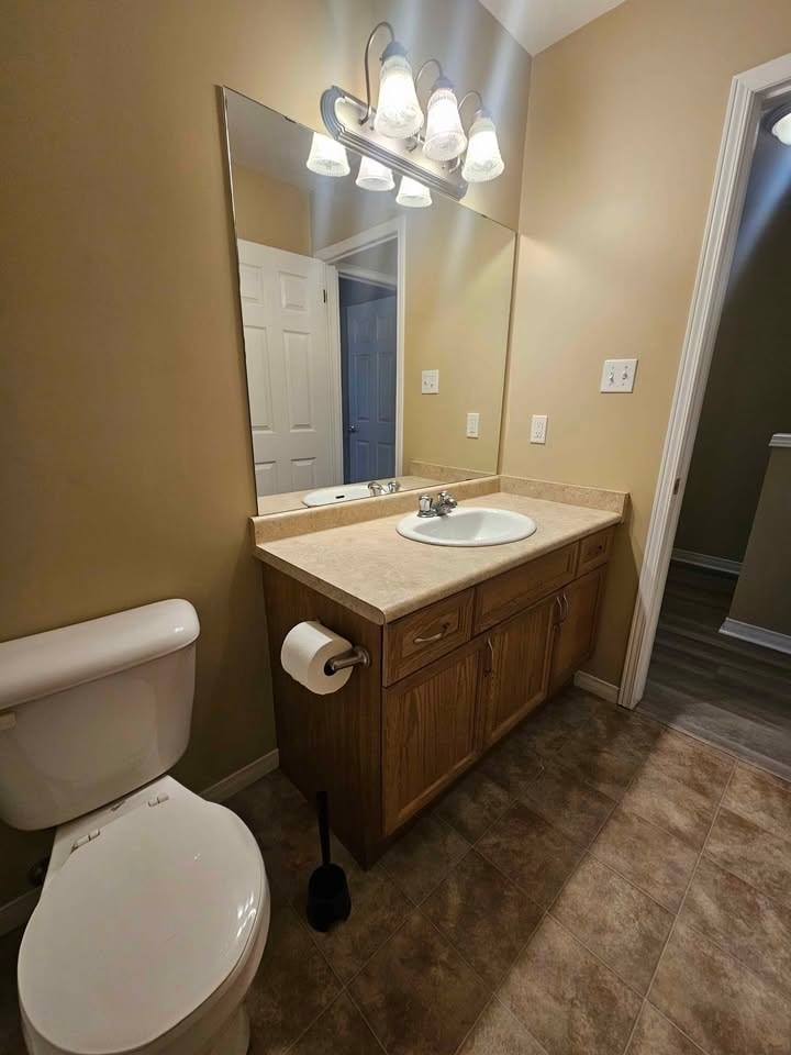 A bathroom with a toilet, sink, and mirror.
