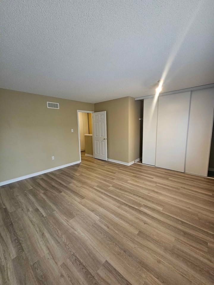 A room with light brown wooden flooring and white walls.