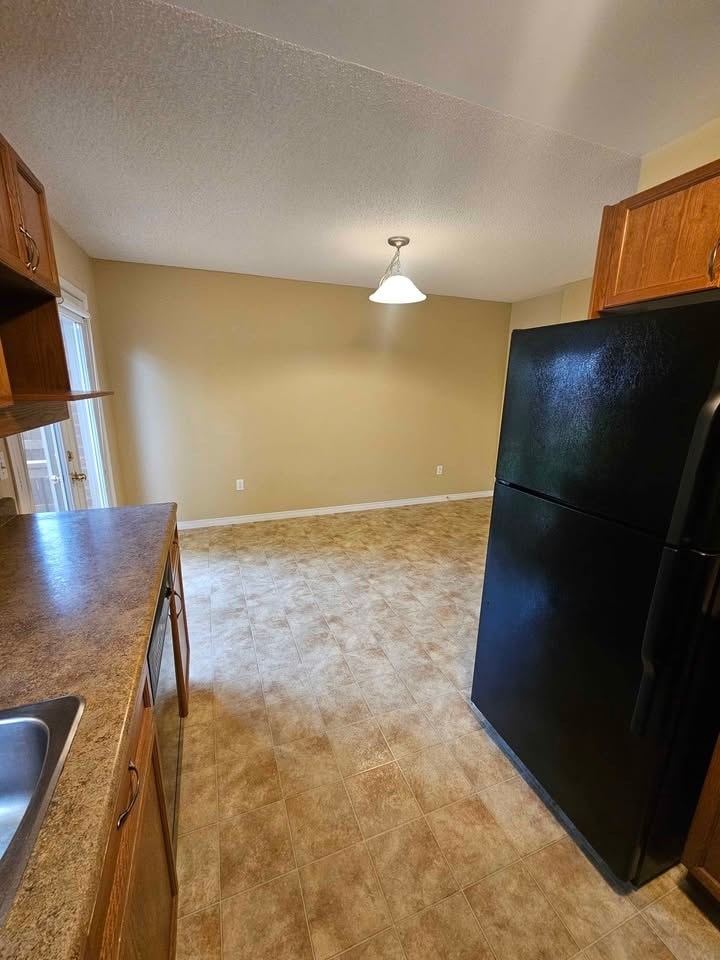 A kitchen with a black refrigerator and brown cabinets.