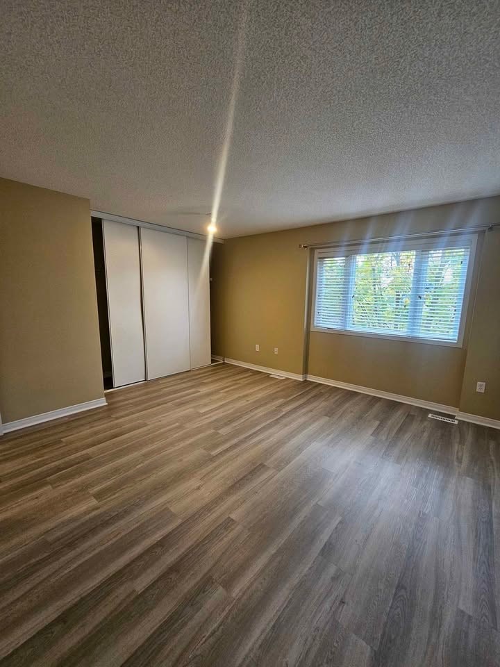 A room with wooden flooring and a window with blinds.
