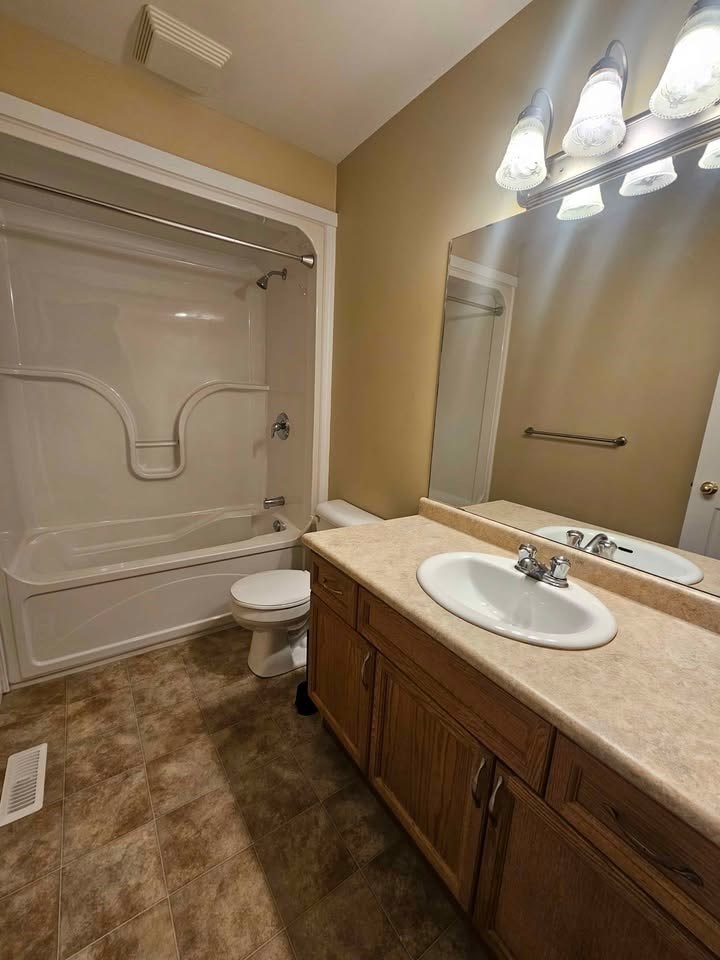 A bathroom with a sink, mirror, toilet and tub.