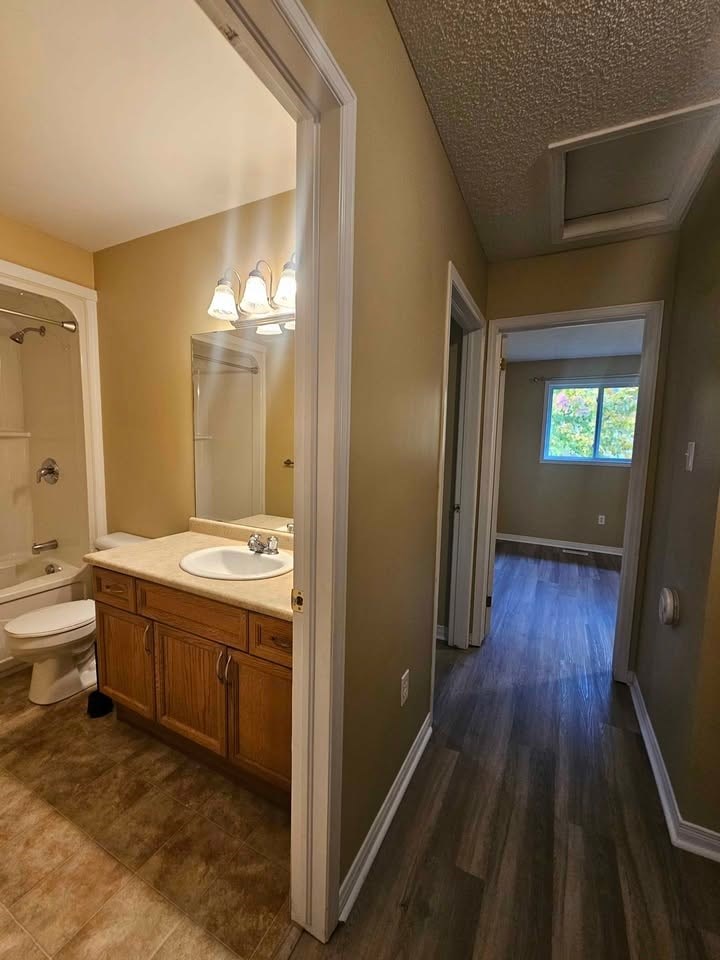 A bathroom with a toilet, sink, and mirror.
