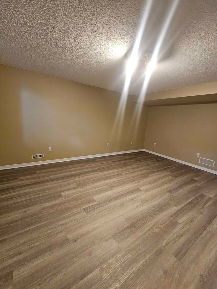 A room with wooden flooring and a light brown wall.