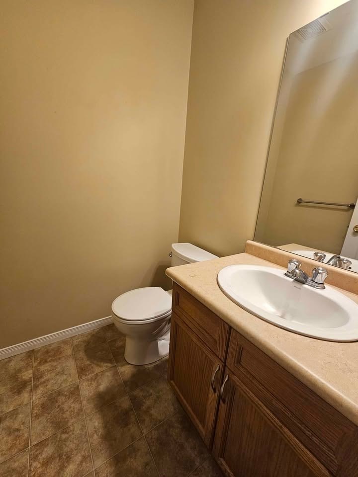 A bathroom with a toilet, sink, and mirror.