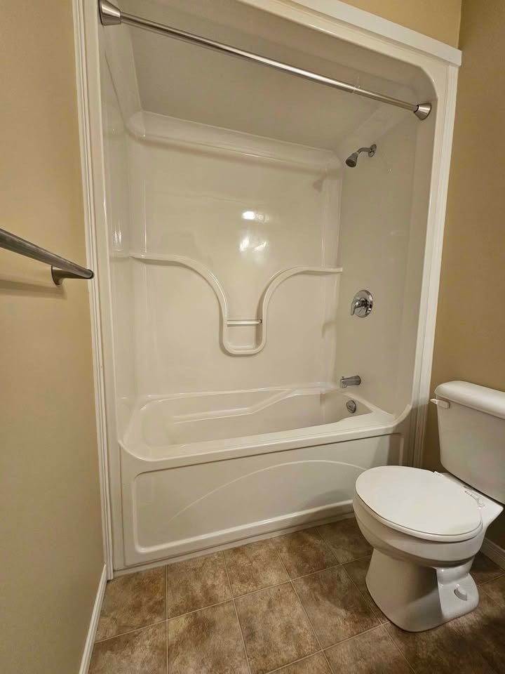 A white toilet is next to a walk-in shower.