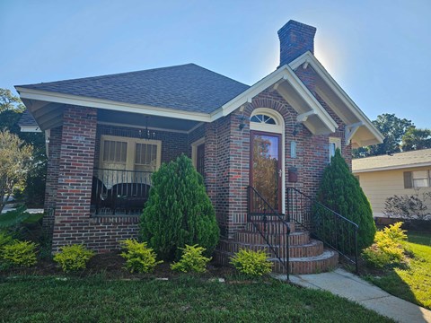 A small house with a brick facade and a black metal railing.