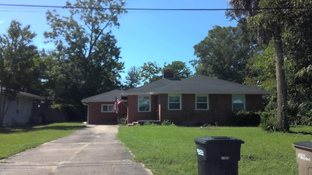A house with a flag on the front and a trash can in front of it.