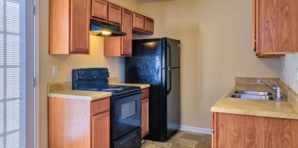 A kitchen with black appliances and wooden cabinets.