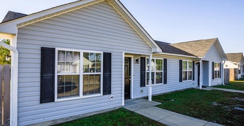 A house with a grey siding and black shutters.