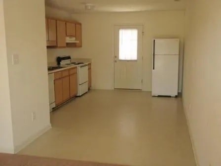 A kitchen with white appliances and wooden cabinets.