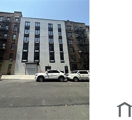 A white car is parked in front of a tall building.