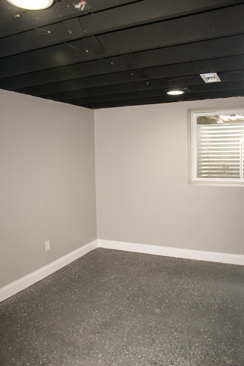 A room with a window and a grey floor.