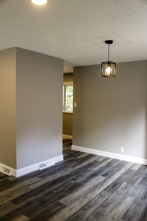 A room with a wooden floor and a hanging light fixture.