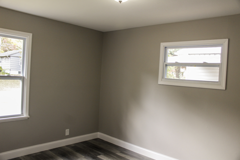 A room with a window and a picture frame on the wall.