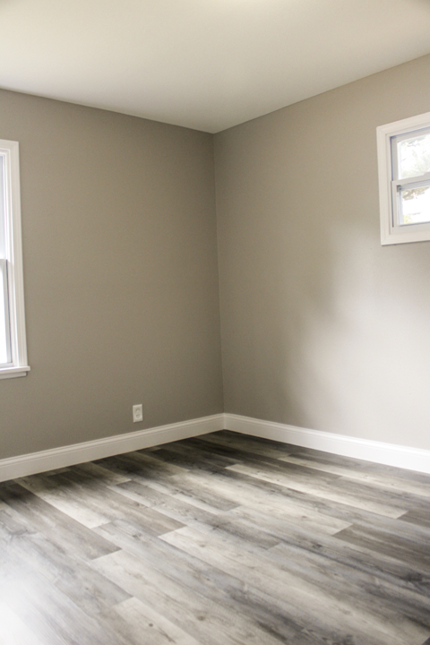 A room with a window and a wooden floor.