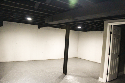 A room with a white door and a black pole in the middle.