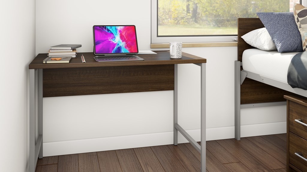 A laptop is open on a desk with a stack of books and a white mug.