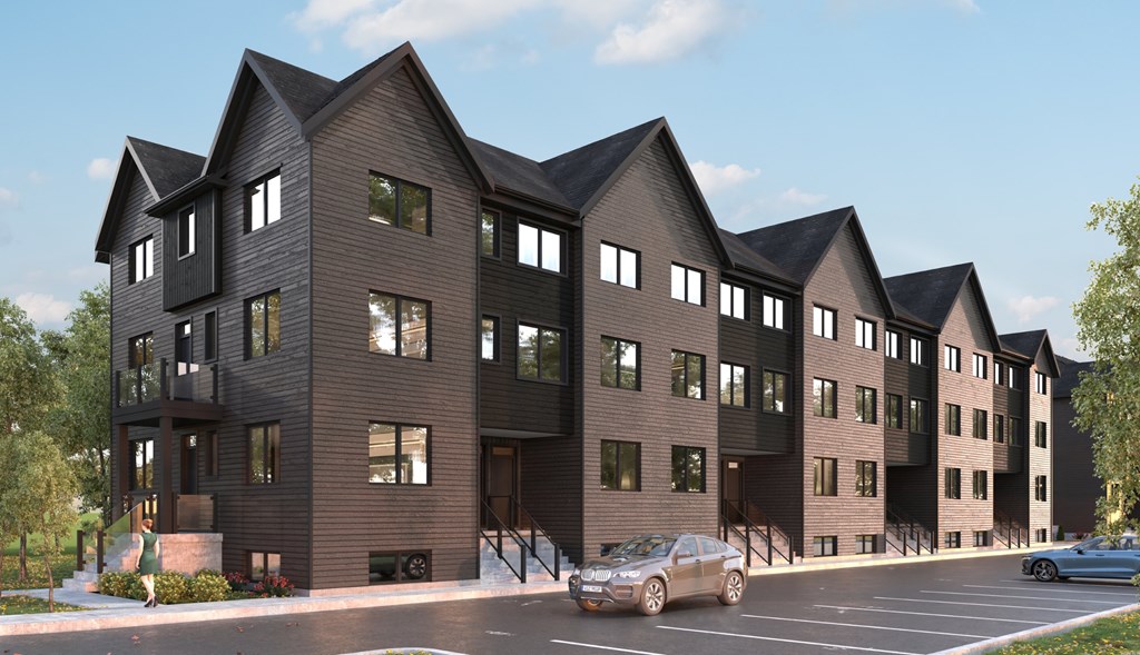 A modern building with a black facade and a parking lot in front.