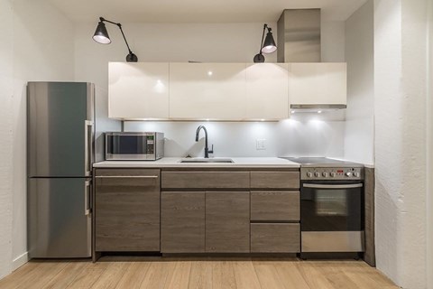 A modern kitchen with a refrigerator, microwave, oven, and sink.