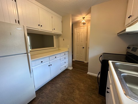 A kitchen with white cabinets and a white refrigerator.