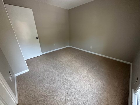 A room with a white door and carpeted floor.