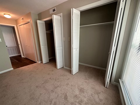 A room with white closet doors and carpeted floor.