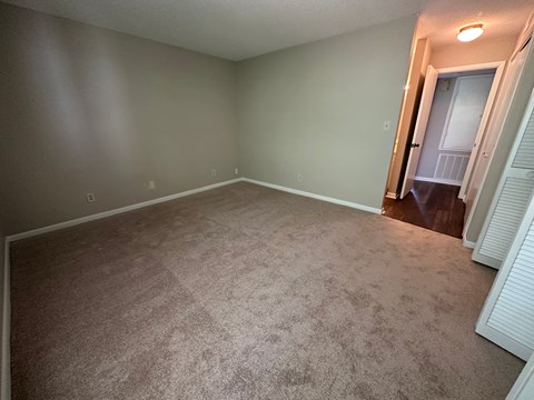 A room with a carpeted floor and a door on the right side.