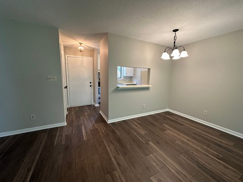 A room with wood flooring and a chandelier.