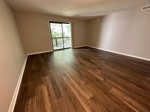 A room with wooden flooring and a sliding glass door.