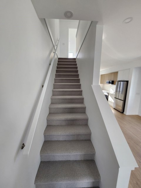 A staircase with grey steps leads to a brightly lit room.