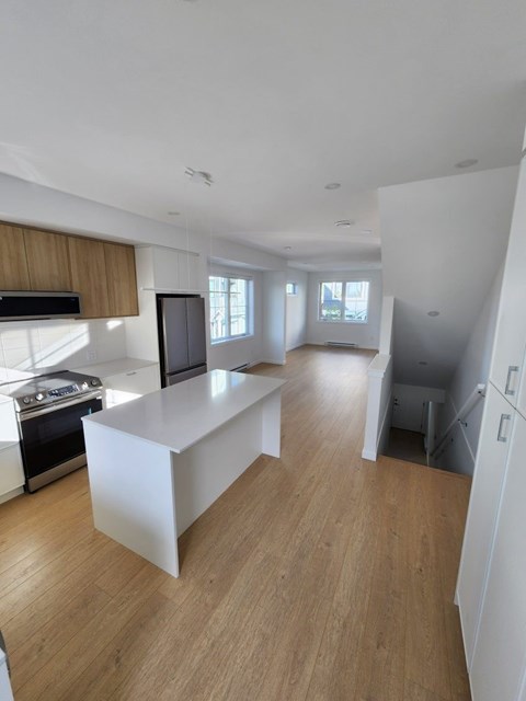 A modern kitchen with wooden floors and white walls.