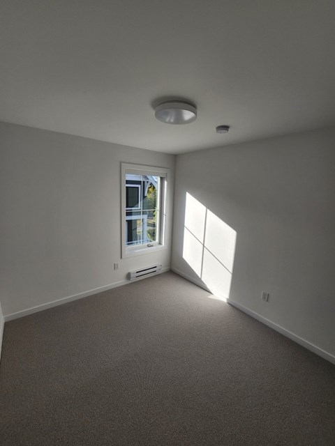 A room with a carpeted floor and a window with blinds.