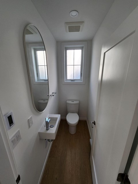 A small white bathroom with a toilet, sink and mirror.