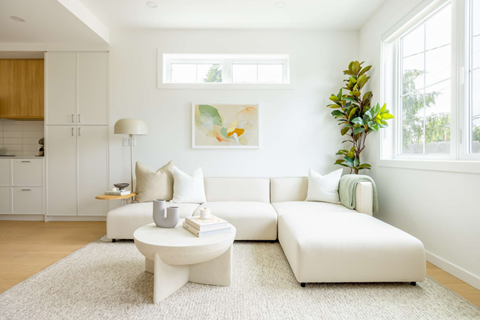 A white living room with a couch, coffee table, and a painting on the wall.