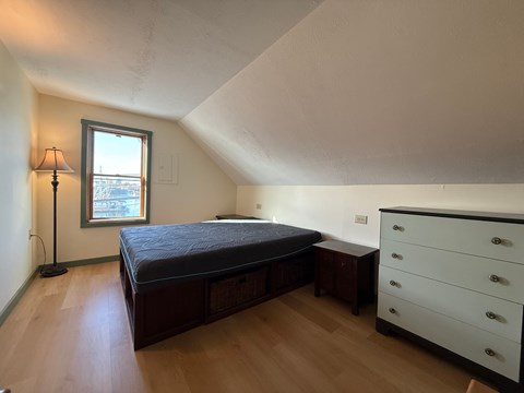A bedroom with a bed, dresser, and window.