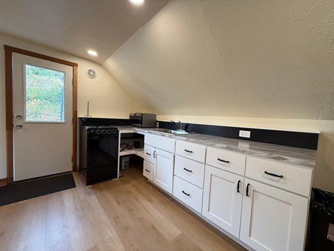 A kitchen with white cabinets and a black fridge.