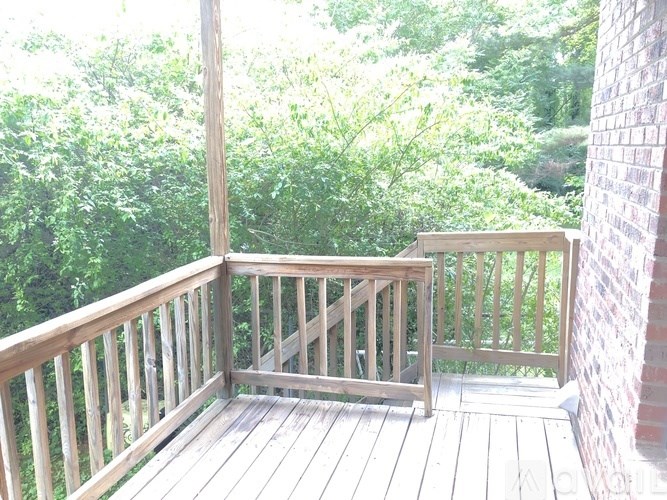 A wooden deck with a bench and a brick pillar.