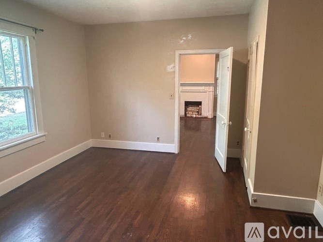 A room with wooden floors and a window on the left side.