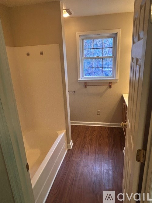 A bathroom with a window and wooden floors.
