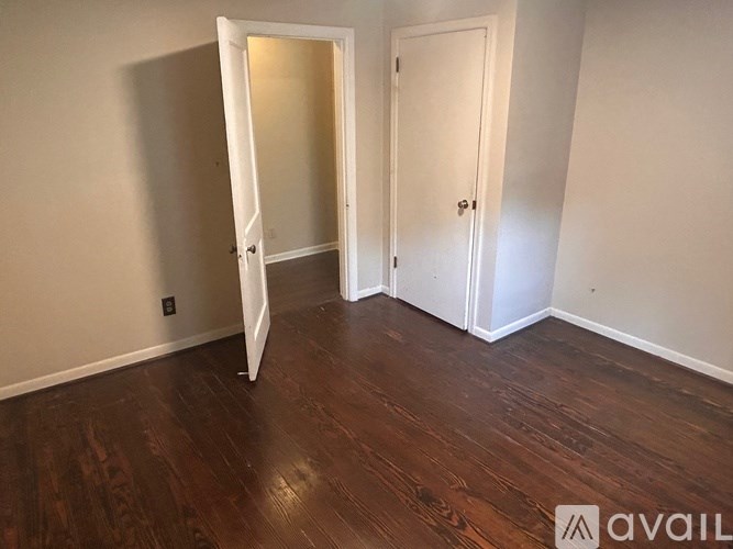 A room with wooden floors and two white doors.