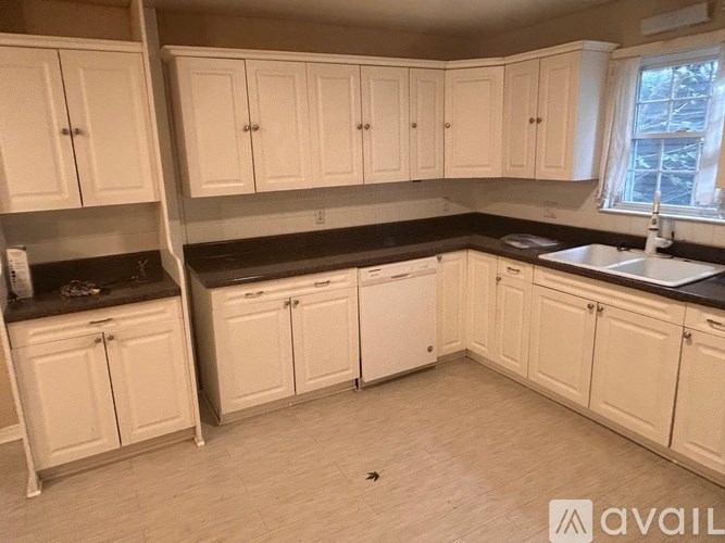 A kitchen with white cabinets and a black countertop.