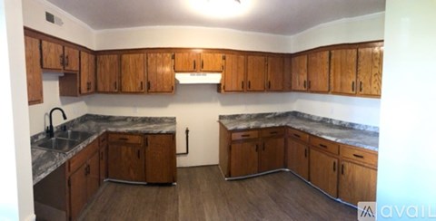 A kitchen with wooden cabinets and a marble countertop.