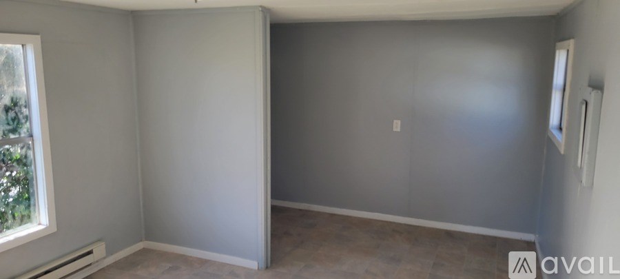 A room with grey walls and a window on the left side.