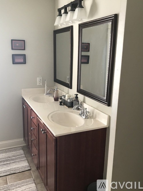 A bathroom with a white counter top and a brown cabinet.