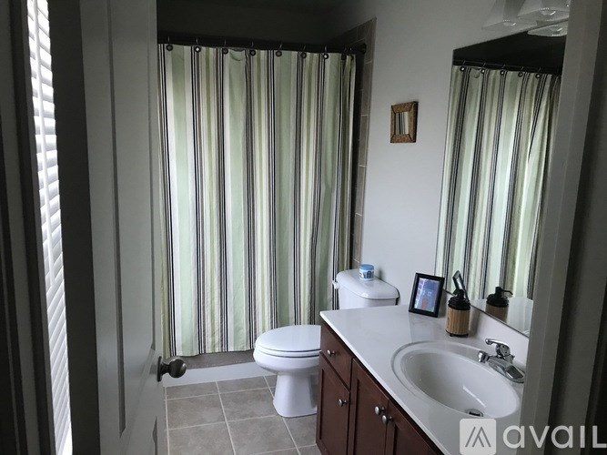 A bathroom with a toilet, sink, and striped shower curtain.