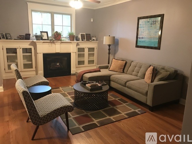 A living room with a fireplace and a grey couch.