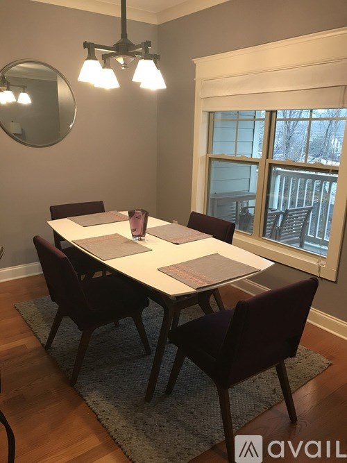 A dining room with a white table and chairs.