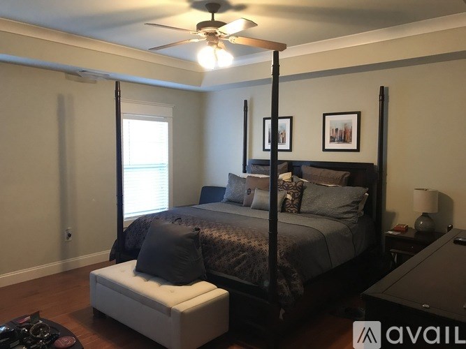 A bedroom with a four poster bed and a ceiling fan.